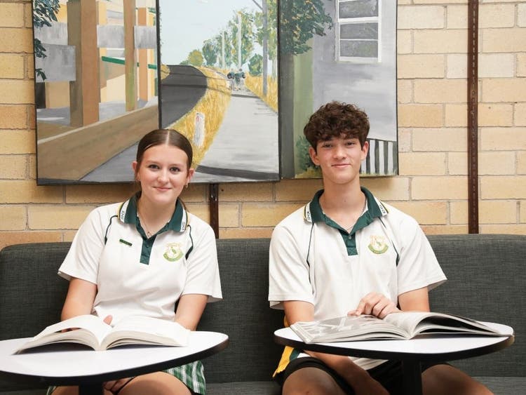 Two students sitting at desks with textbooks open