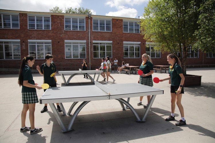 4 students playing table tennis in the quad at school